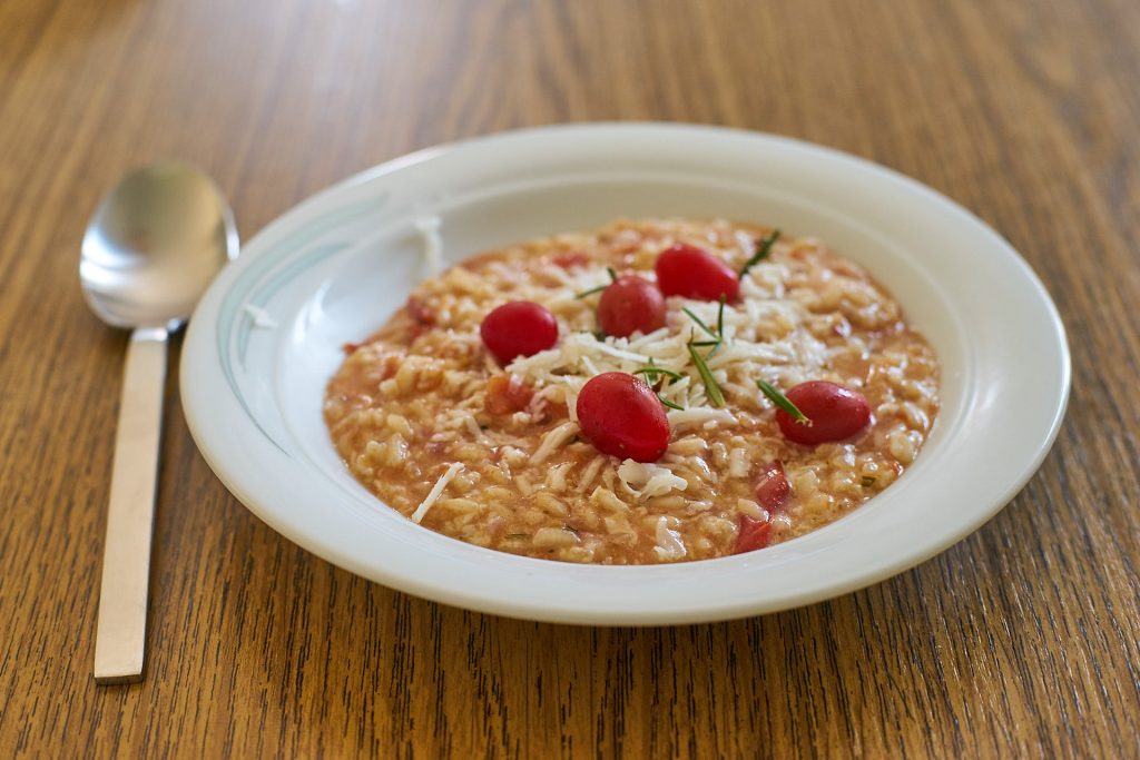 Eine Portion Tomaten-Ziegenkäse-Risotto mit Rosmarin.