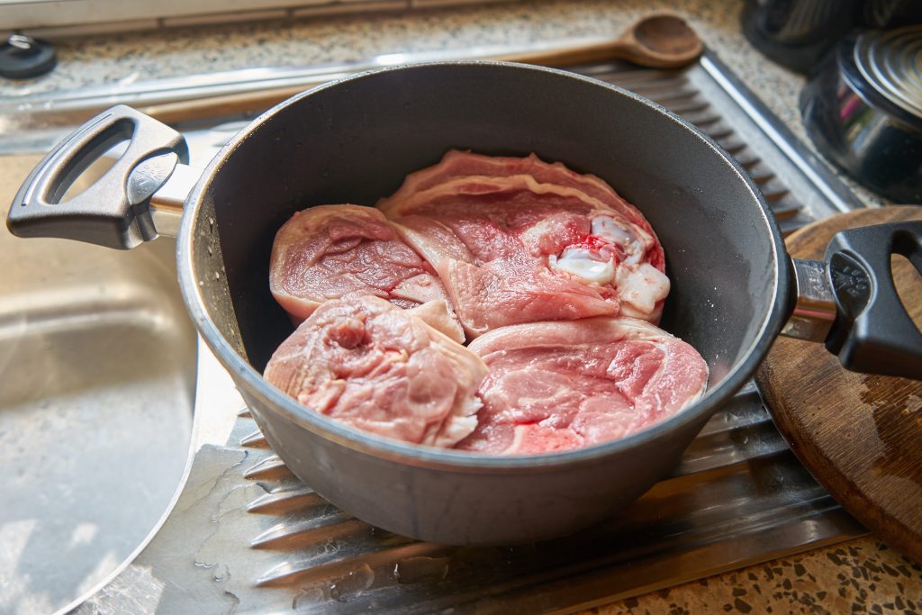 Das Schweinefleisch kommt in einen großen Topf.