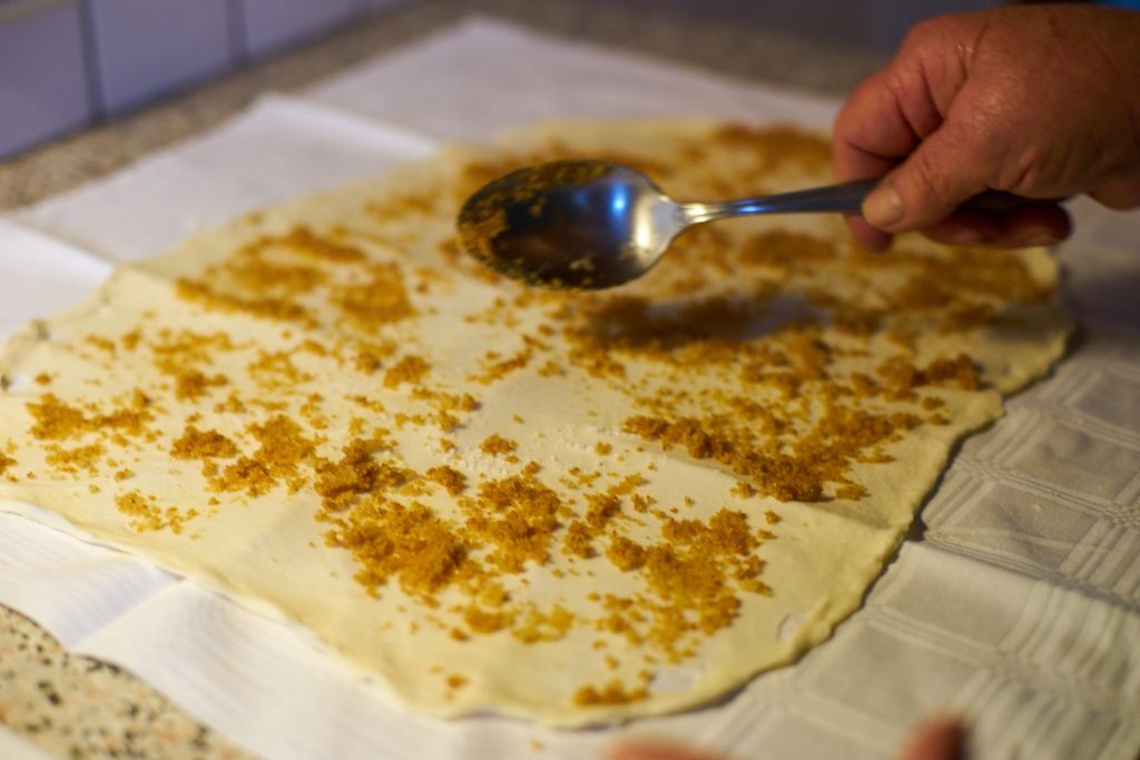 Distributing sugar and cinnamon on the dough.