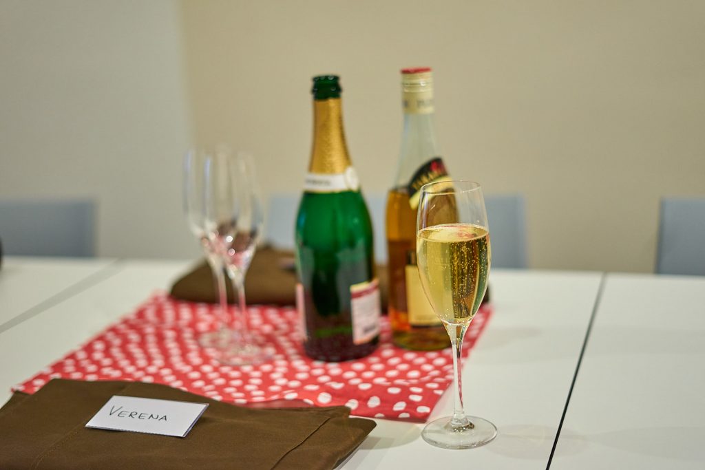 Ein Sektglas - im Hintergrund eine Flasche Sekt und eine Flasche Pflaumenwein. Sushi-Kurs Linz.