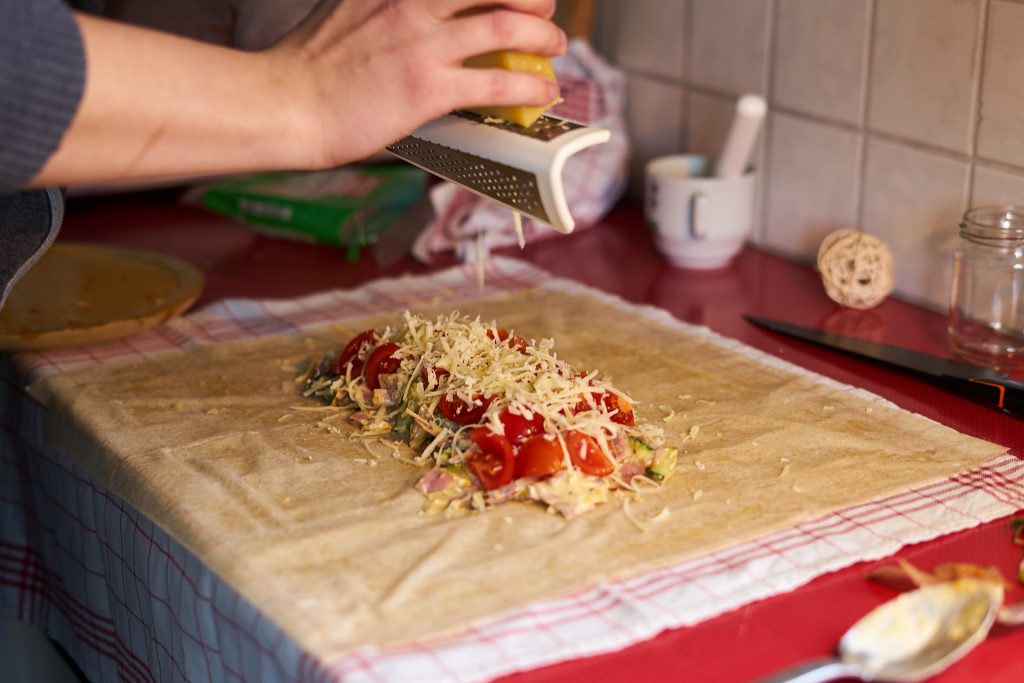 Patrick reibt Käse in den Strudel.