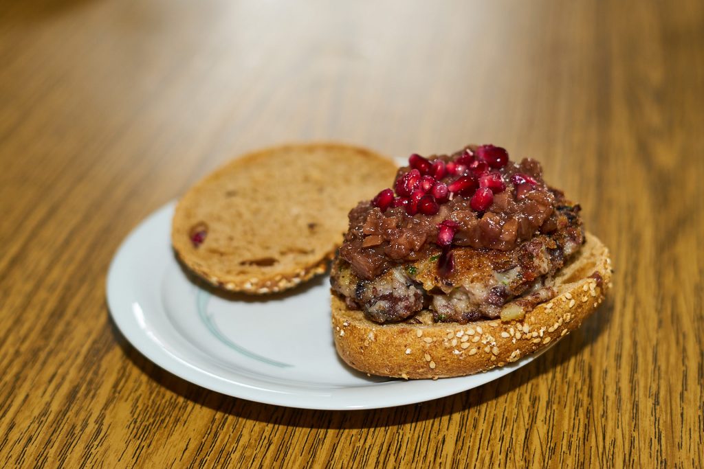 Burgerbrötchen mit Patty, Chutney und Granatapfelkernen.