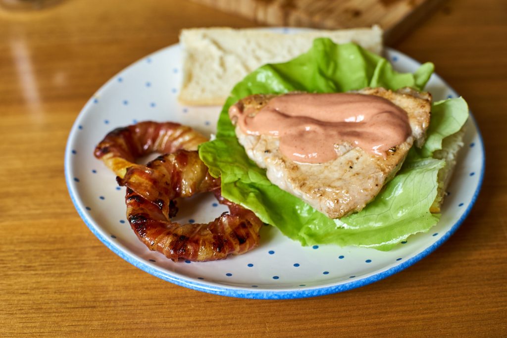 Mahlzeit! Kotelett-Burger mit Zwiebelringen angerichtet.