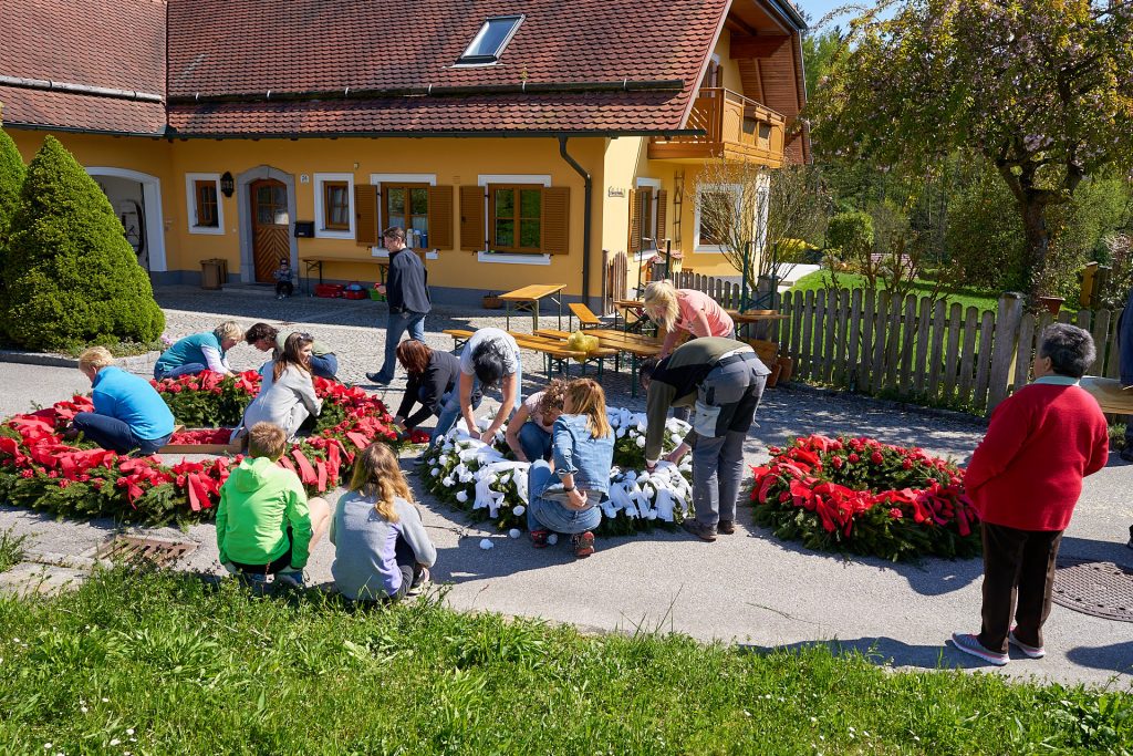 People decorating the wreaths in red and white.