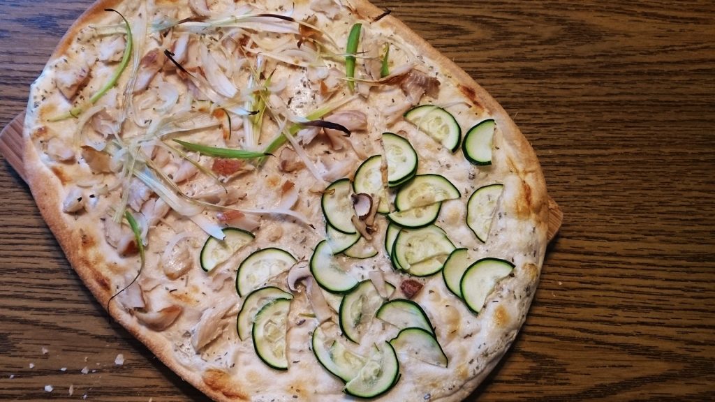 Flammkuchen mit Lauch und Räucherforelle und auf der vegetarischen Seite Zucchini und Champignons