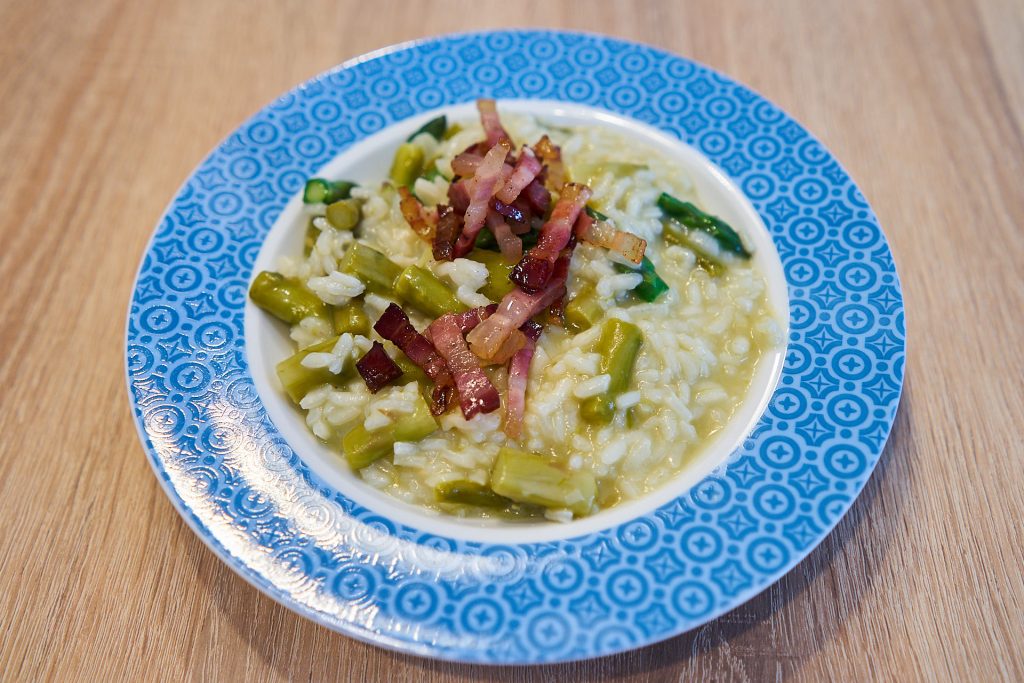 Eine Portion Spargelrisotto mit Speckstreifen